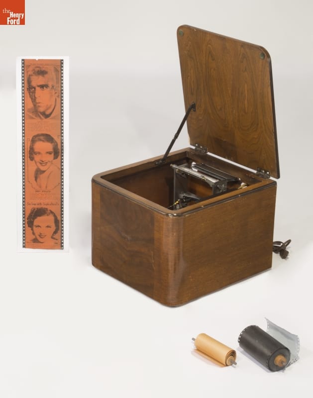 Crosley Reado Radio Printer, 1938-1940 Wooden box with machinery visible inside; two rolls in foreground of picture and strip with images of several faces on left side of image