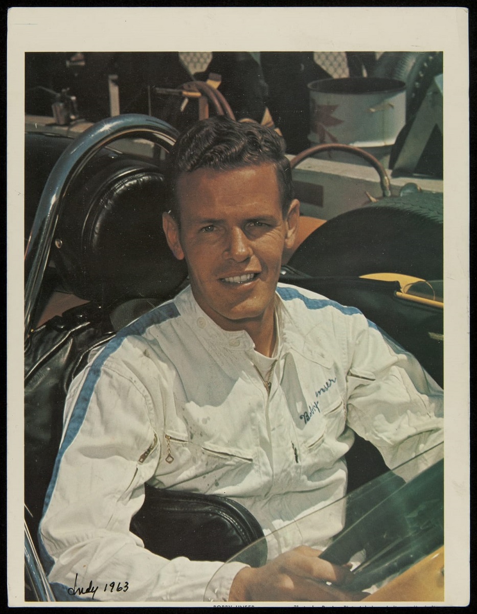 Bobby Unser, 1963 Young man wearing jumpsuit looks at camera as he sits in open race car cockpit