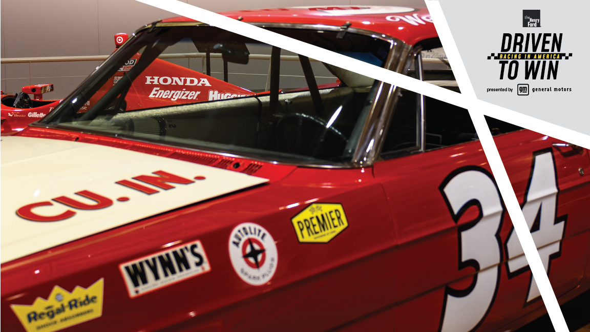 Close-up of windshield, door, and part of hood of red race car with text and logos; features decorative elements and text in upper right