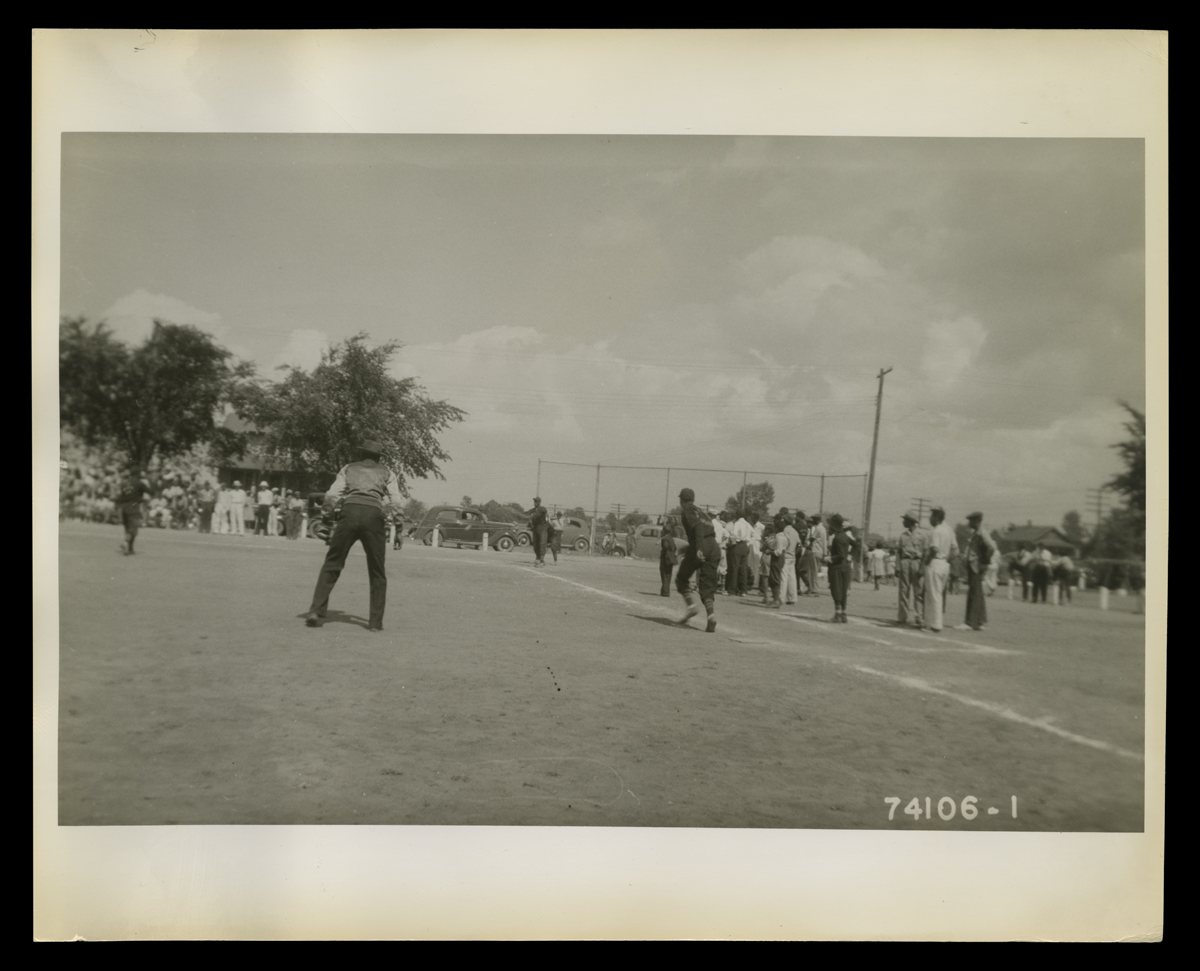 Baseball Game in Inkster, Michigan, July 4, 1940 People, many or all African American, play baseball on a field while others look on