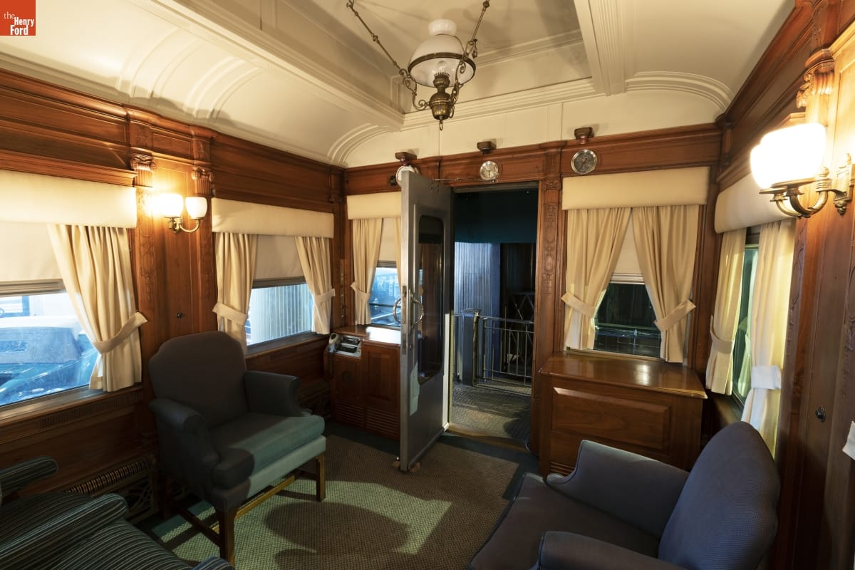 Rail car interior containing chairs, doors, windows, and arched ceiling