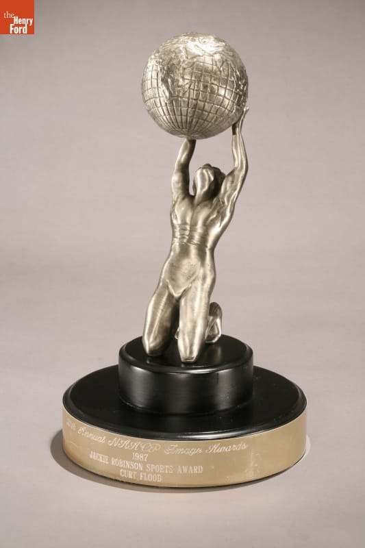 NAACP Jackie Robinson Trophy Awarded to Curt Flood, 1987 Silver trophy of kneeling man holding up a globe on black and silver base with text inscribed