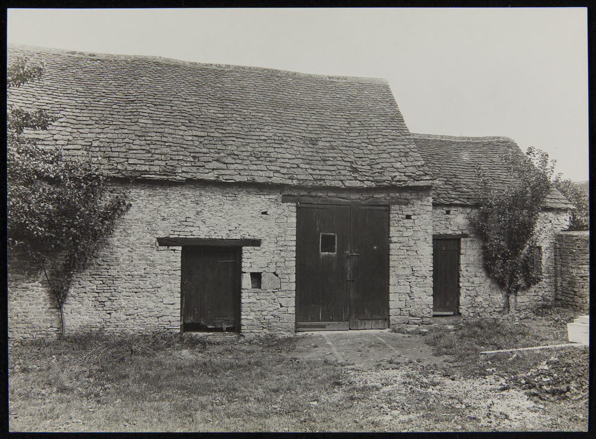 Cotswold Stable at its Original Site, Chedworth, Gloucestershire, England, 1929-1930 Stone building with several wooden doors