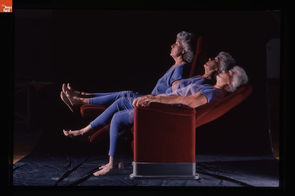 Woman in Motion Study with Prototype Sarah Chair, 1987-1991 Photo with three superimposed images of a woman with gray hair wearing blue scrubs leaning back in a burnt-orange reclining chair