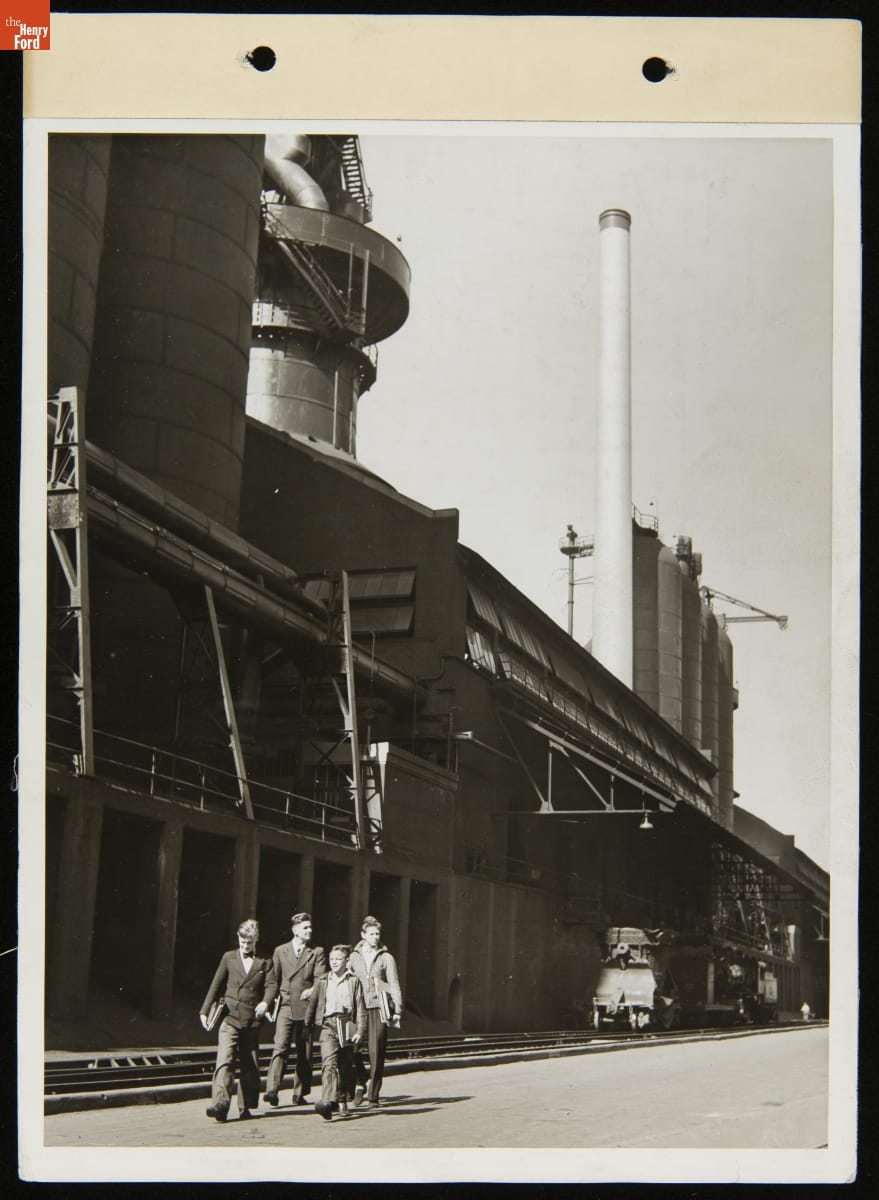 Henry Ford Trade School Students Walking Past the Ford Rouge Plant Blast Furnace, October 6, 1937 Four boys and young men walk alongside a large factory building