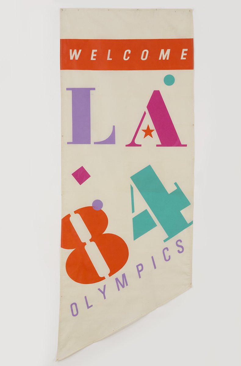 Street Banner for the 1984 Los Angeles Olympics White banner with colorful graphic characters "L A 8 4" and additional text "WELCOME" and "OLYMPICS"