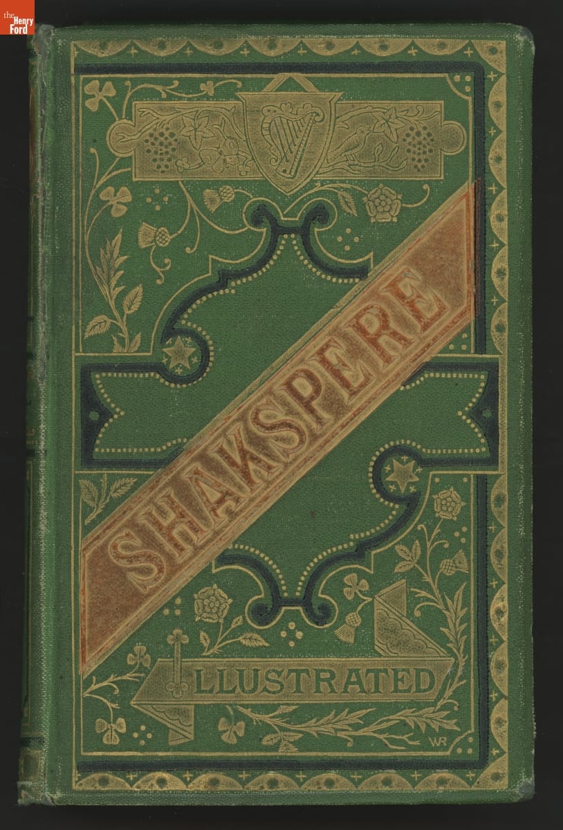 Green book cover with brown band reading "SHAKSPERE" and other text as well as decorations in black and gold