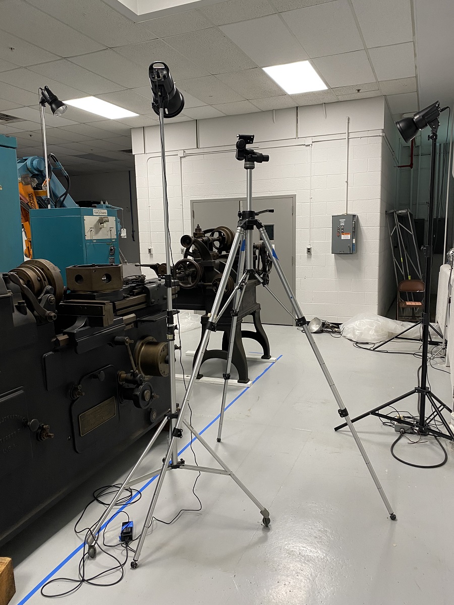 A Pratt & Whitney Gear Cutter and Lathe, circa 1900, getting set up for photography in storage Tripods with lights pointed at machinery, with more machinery at side