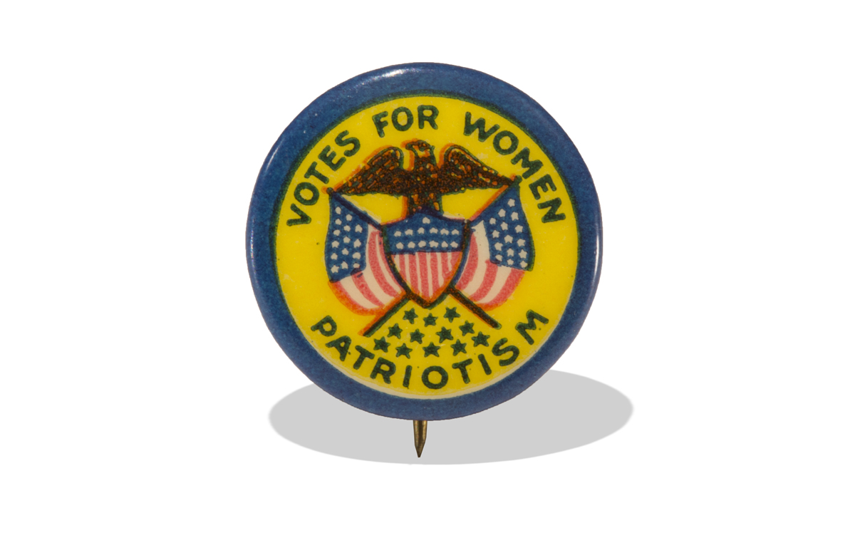 Button, "Votes for Women: Patriotism," circa 1910 Button with image of eagle over crossed red, white, & blue American flags and shield, yellow background and blue rim, with text “Votes for Women – Patriotism”