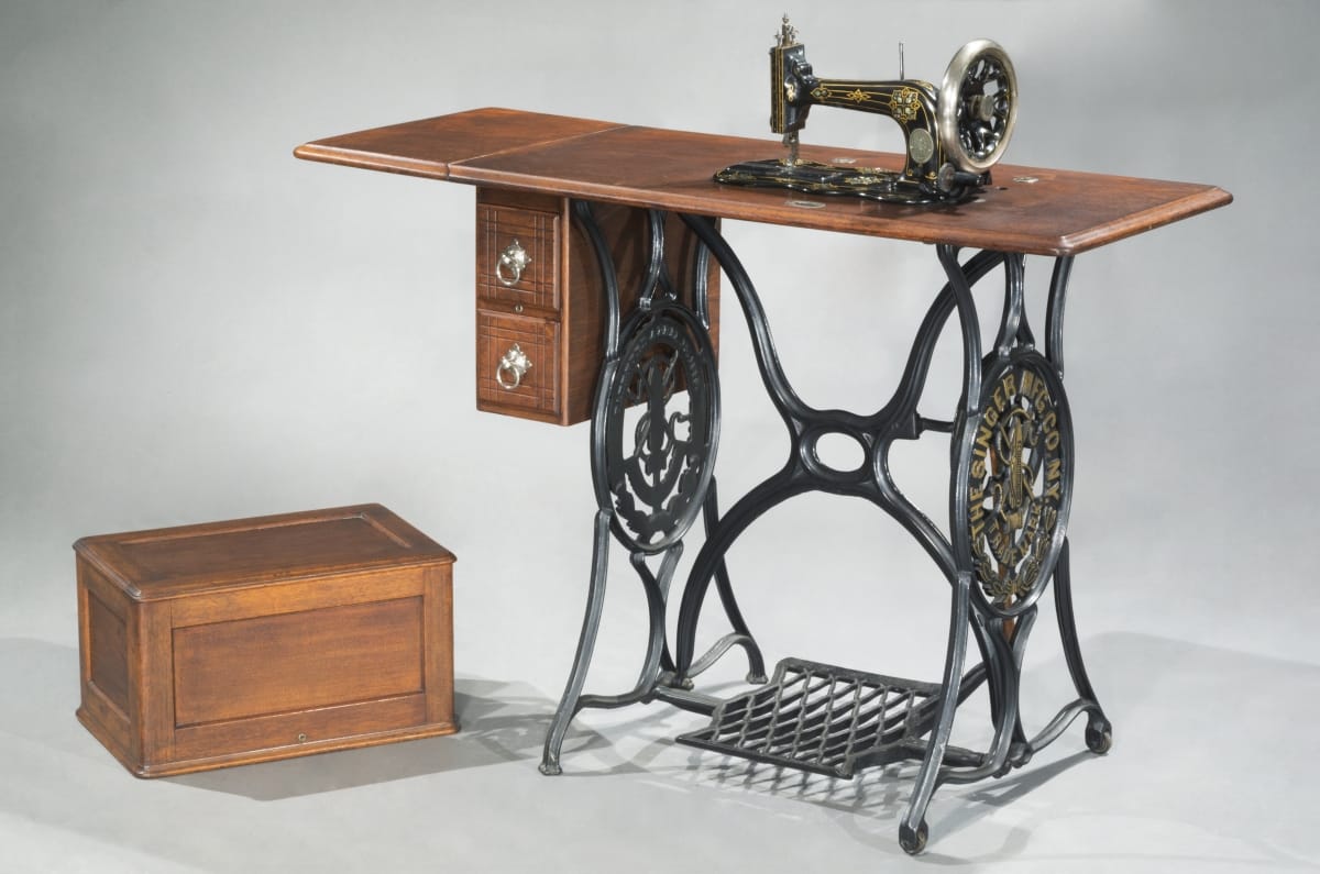 Singer Sewing Machine, 1881 Sewing machine built into wooden table with intricate, decorative metal base