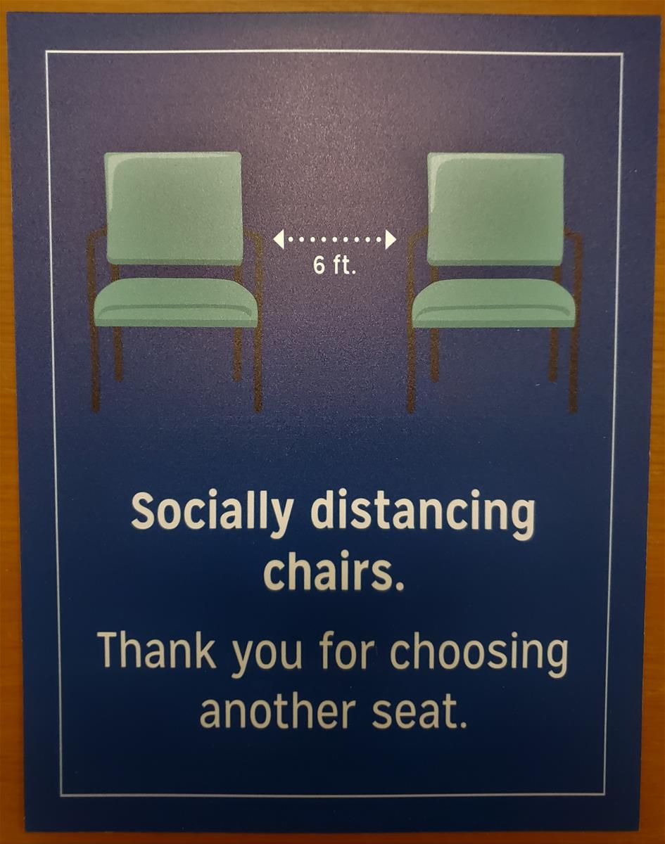 Poster showing two green chairs with dotted lines denoting six feet between them; also contains text