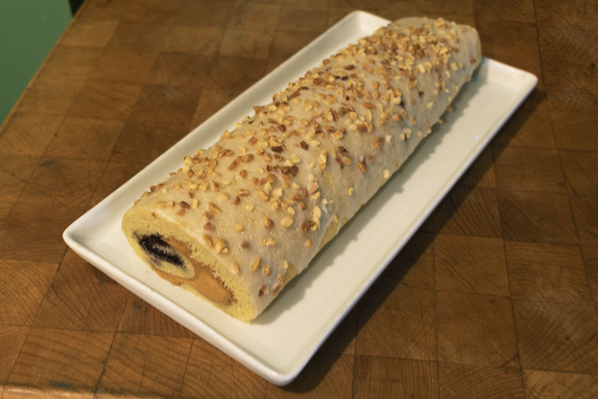 Peanut Roll Cake with Jelly Rolled cake topped with peanuts and with peanut butter/jelly filling visible at end