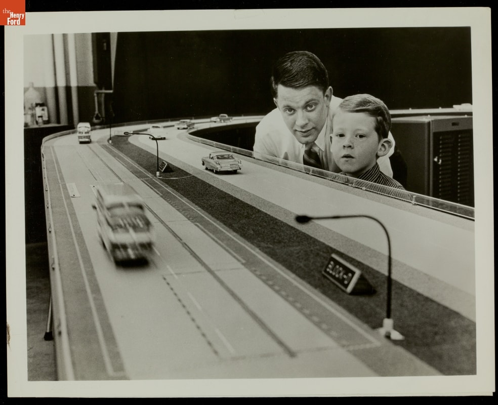 Young Boy Viewing General Motors Model Highway, 1959 Young boy and young man look at eye level at a large model of a road with cars