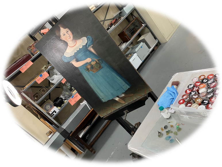 Getting set up to inpaint Oval image of painting of girl in blue dress on an easel; table nearby with palette and tubes of paints