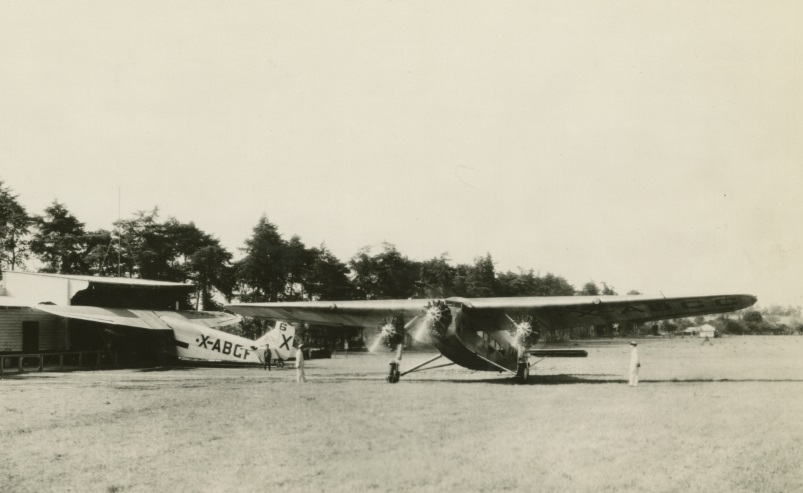 Ford Tri-Motor Airplanes at Airport, 1930 (detail) Two planes and several people in open field near low building