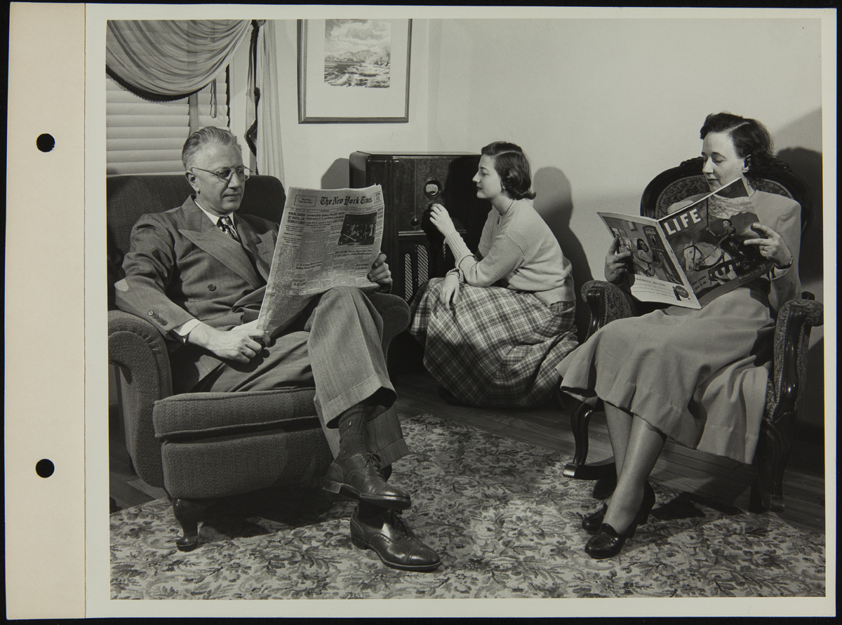 Allan McGrew and Family Reading and Listening to Radio, 1948 Man and woman sitting in chairs, reading, while teen girl kneels by a radio