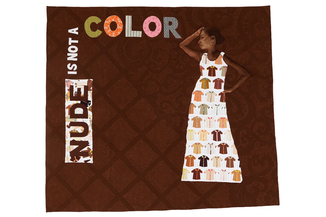 Brown quilt with quilted text "NUDE IS NOT A COLOR" and image of brown-skinned woman in pale dress covered with smaller images of shirts in many shades 