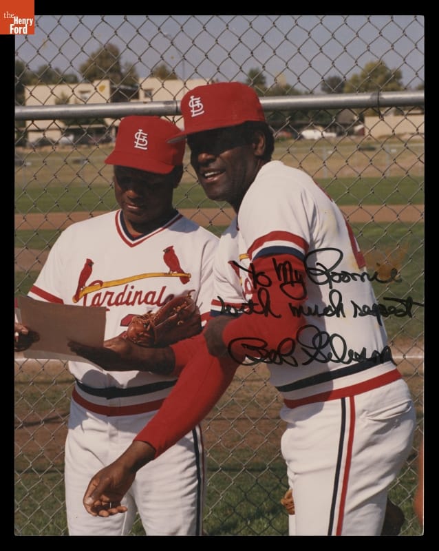 Portrait of Curt Flood and Bob Gibson, Inscribed to Flood by Gibson, 1967-1968 Two dark-skinned men in red and white baseball uniforms stand in front of a baseball field