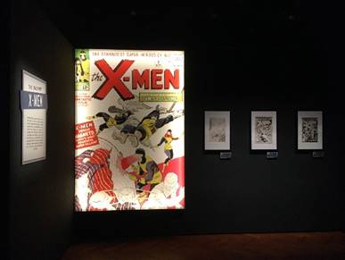 X-Men section of the "Marvel: Universe of Super Heroes" exhibition Oversized, illuminated comic book cover with images and text; framed text and images on walls on either side