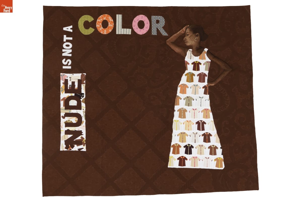 "Nude is Not a Color" Quilt, Made by Hillary Goodwin, Rachael Dorr, and Contributors from around the World, 2017 Brown quilt with text "NUDE IS NOT A COLOR" and quilted image of woman wearing dress with many short-sleeved shirts on it