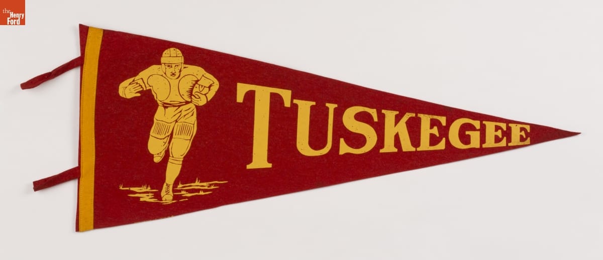 Tuskegee Institute Football Pennant, 1920-1950 Red triangular pennant with yellow text "TUSKEGEE" and image of football player