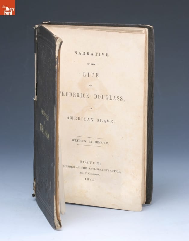 Book standing on end, open to title page, which contains text