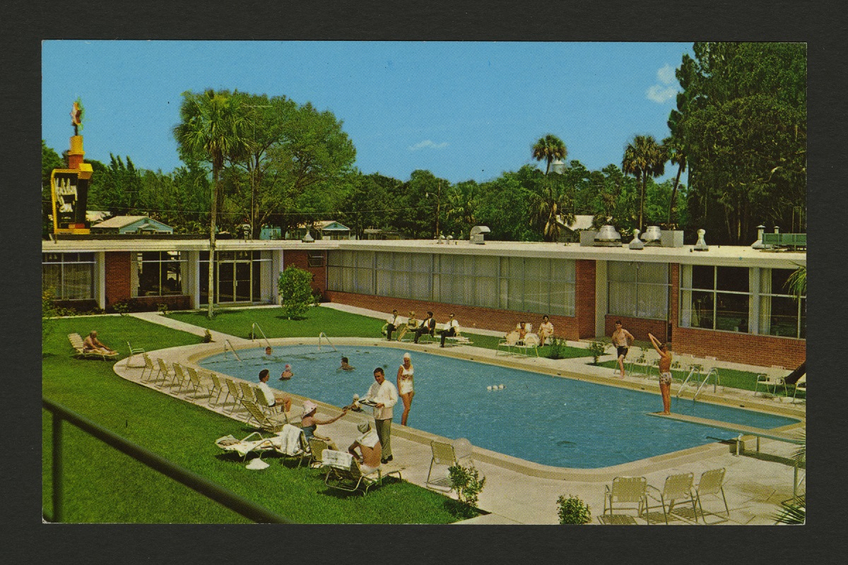 Swimming Pool at Holiday Inn of Daytona Beach, Florida, 1961 L-shaped low brick building bordering grassy area containing swimming pool with people in and around it