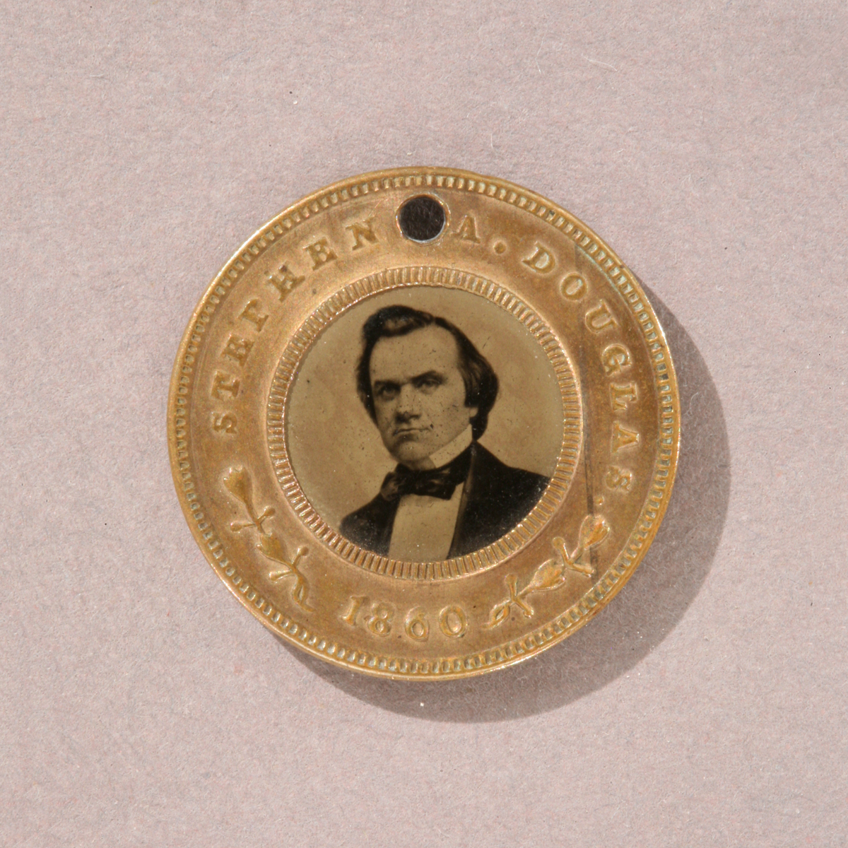 Douglas-Johnson Campaign Badge, 1860 Round gold token with image of man’s shoulders and head in the middle and text “Stephen Douglas 1860” around edge