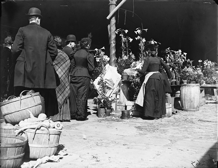 Flower shoppers at Detroit's Central Market Men and women crowd around tables displaying potted lilies and cut flowers in an open-air market