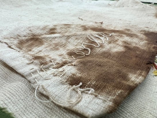 Squiggles on the right pocket Beige fabric with dark brown staining and squiggly stitching