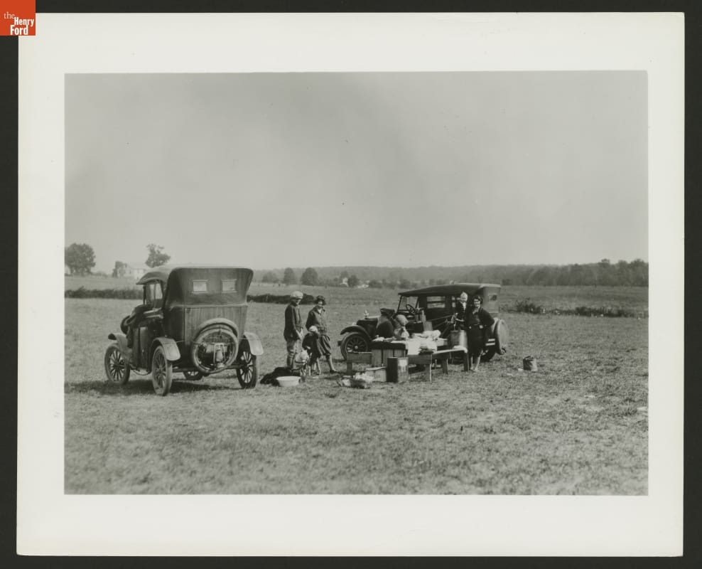 Makeshift Auto Camping with Ford Model T Cars, circa 1925 Small group of people in a field with two cars and a table covered in gear