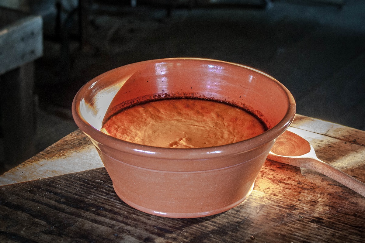Carrot Pudding Redware dish containing orange baked pudding, sitting on a wooden table