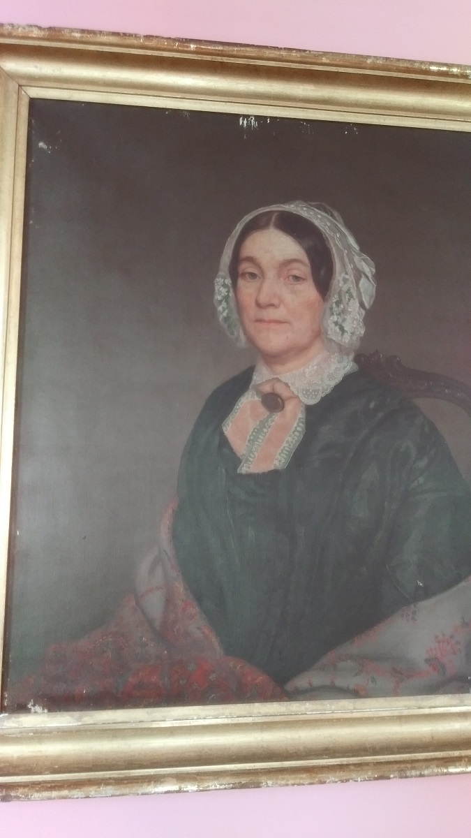 The original photo from The Henry Ford's clean team, showing damage to the painting Quick off-center snapshot of painting of woman in black dress, shawl, and white bonnet, showing damage at top of painting