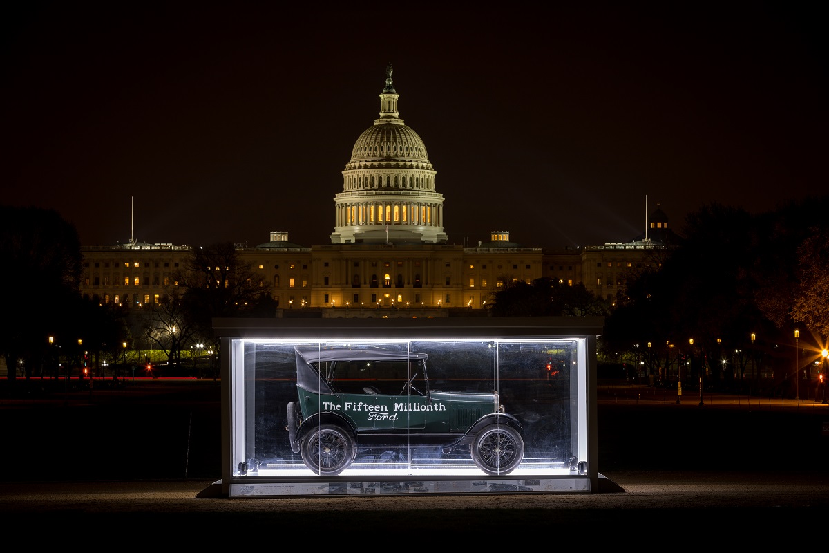 The 15 Millionth Ford Model T on the National Mall in Washington, D.C., in April 2018 Green Model T car with writing on sides in a large glass case at night on a pathway with the U.S. Capitol lit up behind it