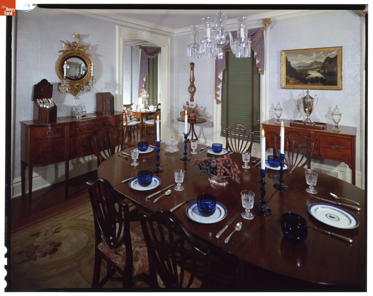 Room containing large wooden dining room table with table settings, two sideboards, and more furnishings