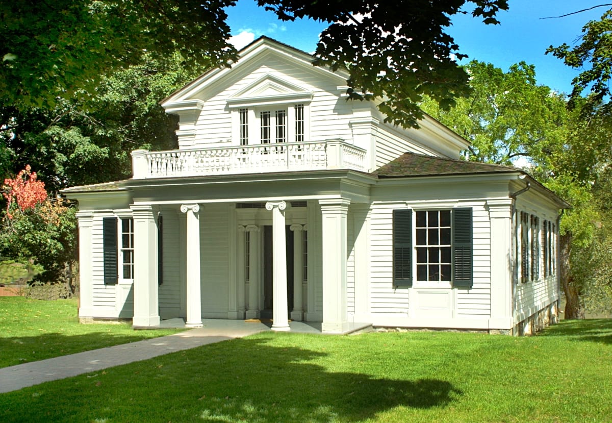 Robert Frost Home Two-story white wooden house with elaborate portico with columns, topped by a balcony