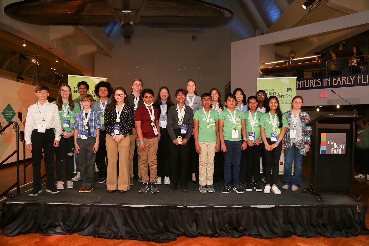 The award winners of Invention Convention Michigan 2022 A group of children stand on a low stage and pose for the camera