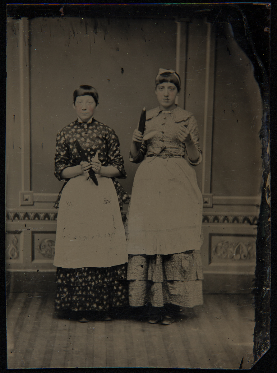 Two Textile Workers with Spindles of Yarn, circa 1870 Two women with short hair wearing dresses and aprons holding spindles