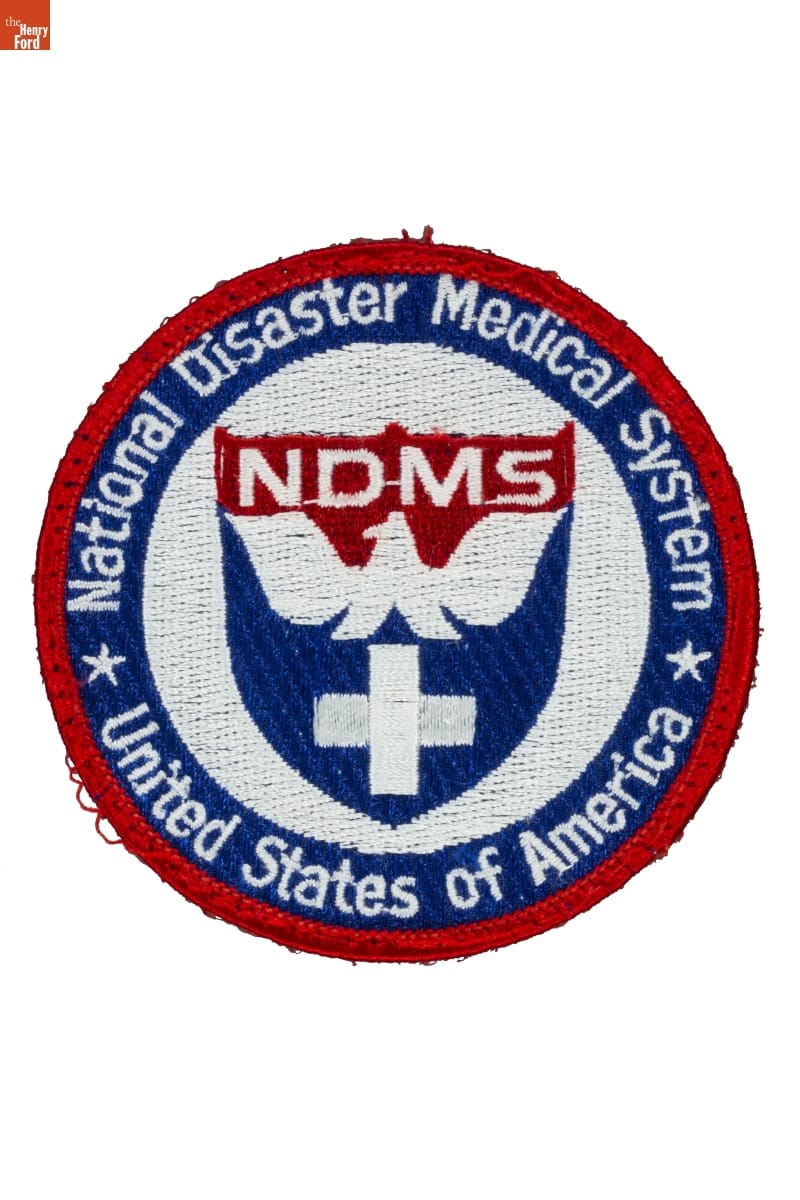 "National Disaster Medical System" Patch, Worn by Gerald Gomes While on Assignment at Ground Zero, September 2001 Red, white, and blue round fabric patch with shield containing cross and bird in center; also contains text