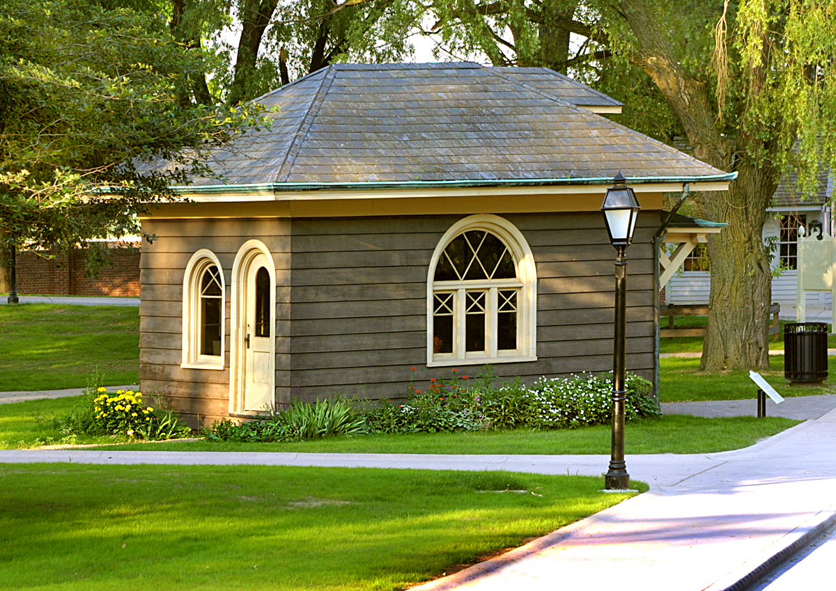 Luther Burbank Garden Office Small gray wooden building with arched windows and door