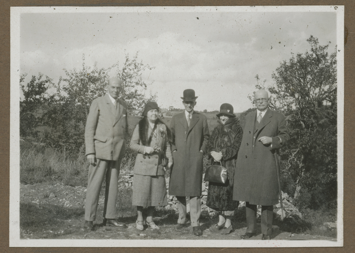Photograph Album, Henry and Clara Ford's Visit to the Cotswolds, October 1930 / page 17 Group of people pose for photo in front of bushes