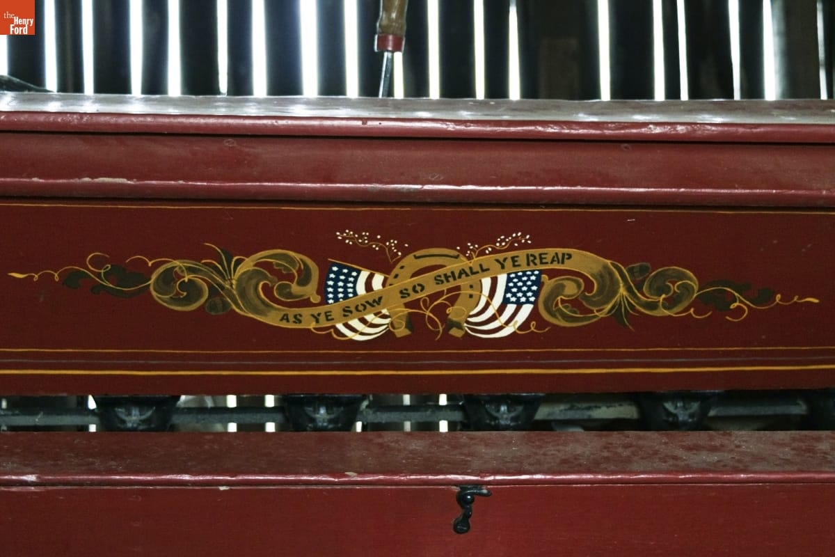 Bickford & Huffman Grain Drill, circa 1890 / detail Brown or maroon wooden equipment with text "As Ye Sow So Shall Ye Reap" against decorative gold scrolling, two American flags, and a horseshoe