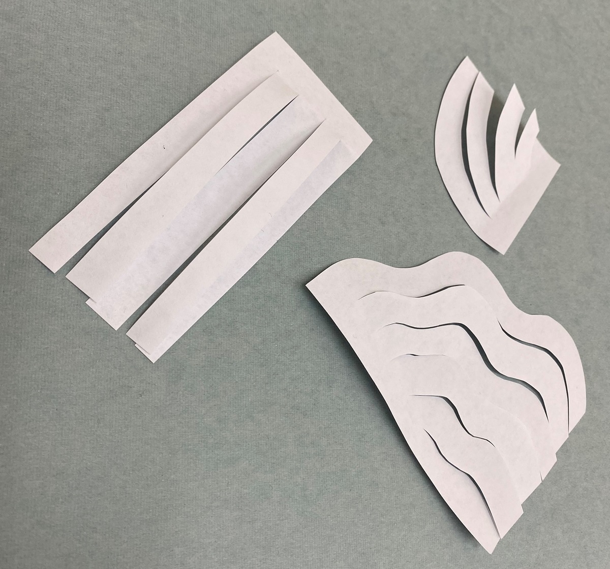 Our paper-cutting experiments for the wig White paper cut into straight strips, half-arc strips, and wavy half-arc strips