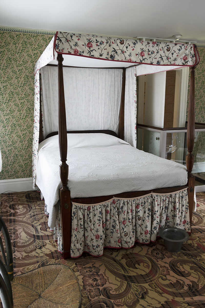 Canopy bed in a room with patterned carpet and wallpaper