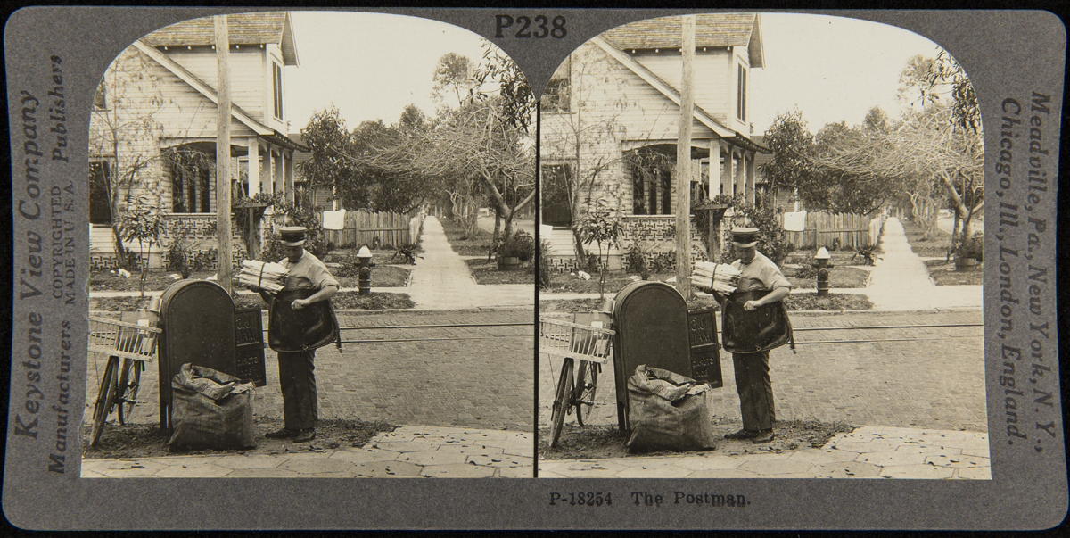 "The Postman," circa 1925 Double arch-shaped image of postman by mailbox on a residential street adding items to mailbag; a bike leans against postbox and a large sack is nearby