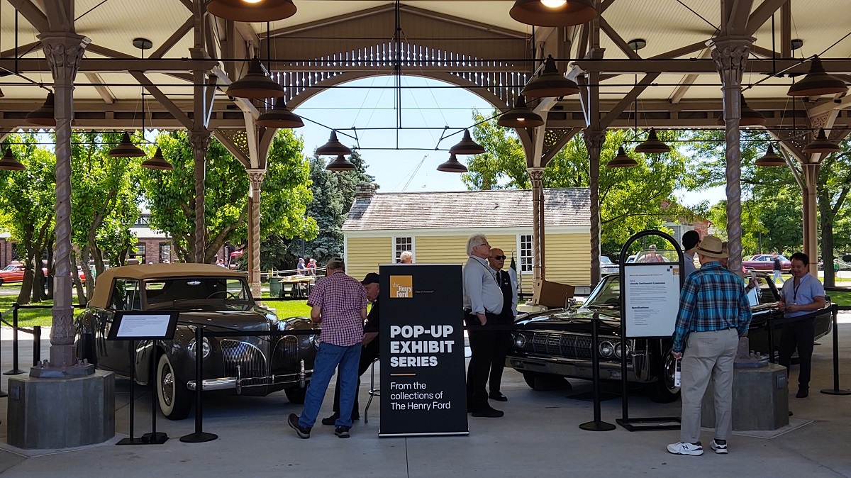 Two Lincoln Continentals from The Henry Ford’s collection at Motor Muster 2022 Onlookers check out two cars behind stanchions with signage under a large open shed