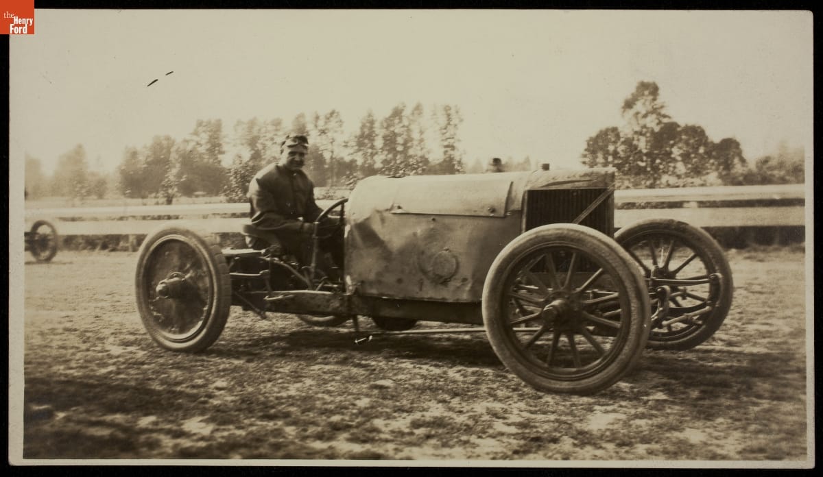 Barney Oldfield Behind the Wheel of the Peerless "Green Dragon" Racecar, circa 1905 Man sits behind wheel of early open race car on a dirt track