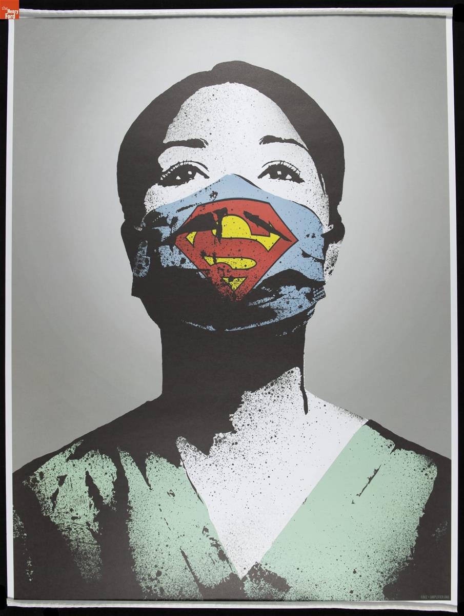 Portrait of woman with dark hair in green scrubs wearing blue face mask marked with yellow and red "Superman" symbolic S