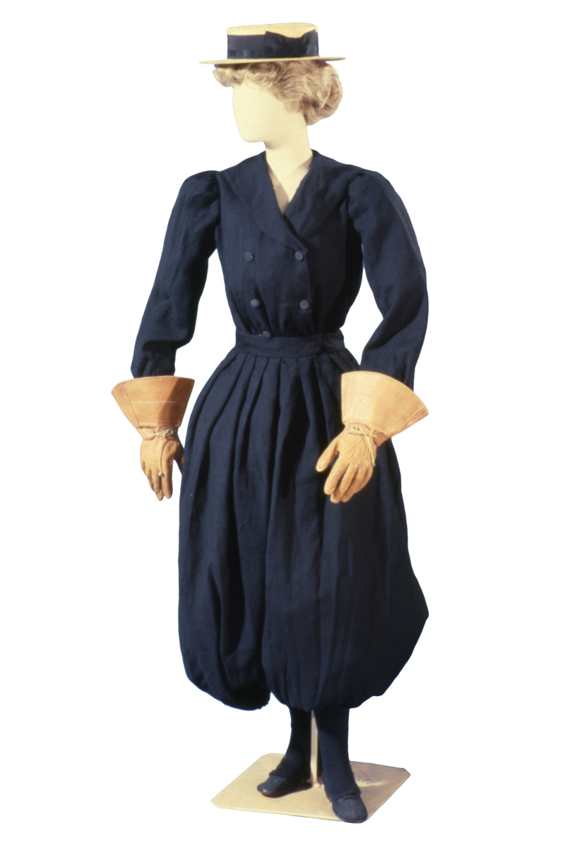 Women's Cycling Suit, circa 1900 Mannequin wearing blue outfit with puffy bloomers, jacket with four button placket, large gloves, and a straw hat