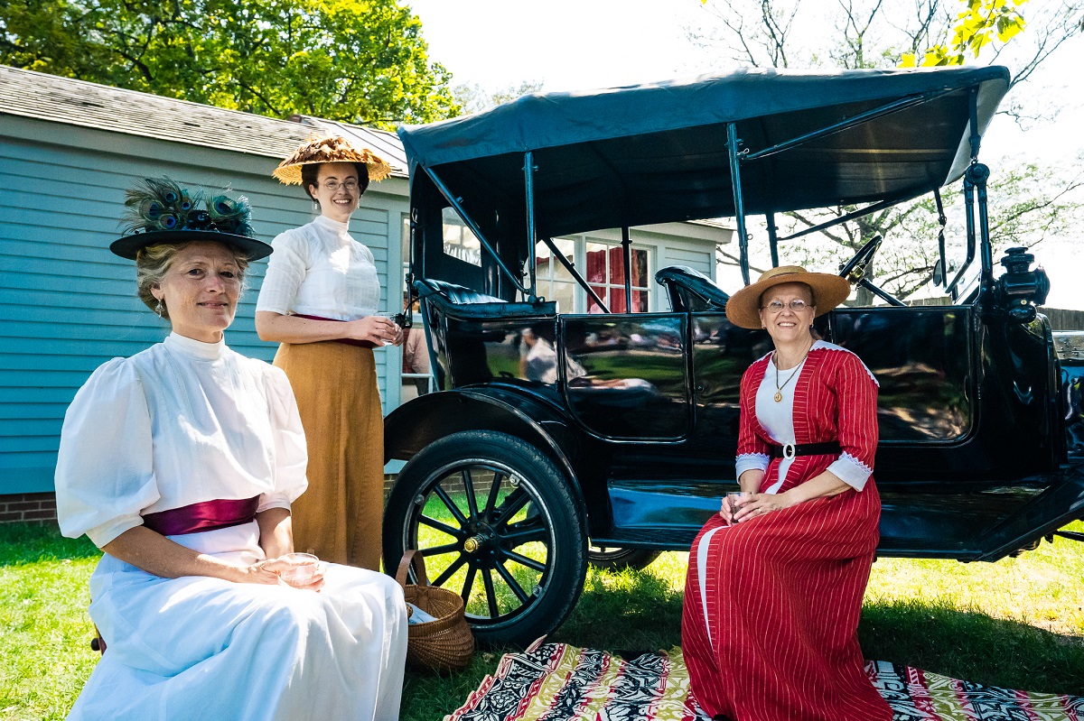 Women representing at Old Car Festival 2021 Three women in historic clothing and hats sit and stand by/on a black car